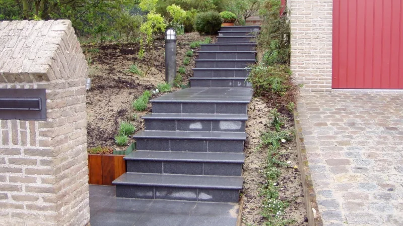 Dicht beplante border met bodembedekkers en heesters langs een klinkerpad