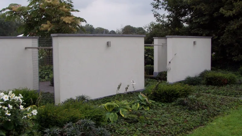 Snoeischaar bij een strak geschoren haag met herfstkleurige heesters op de achtergrond